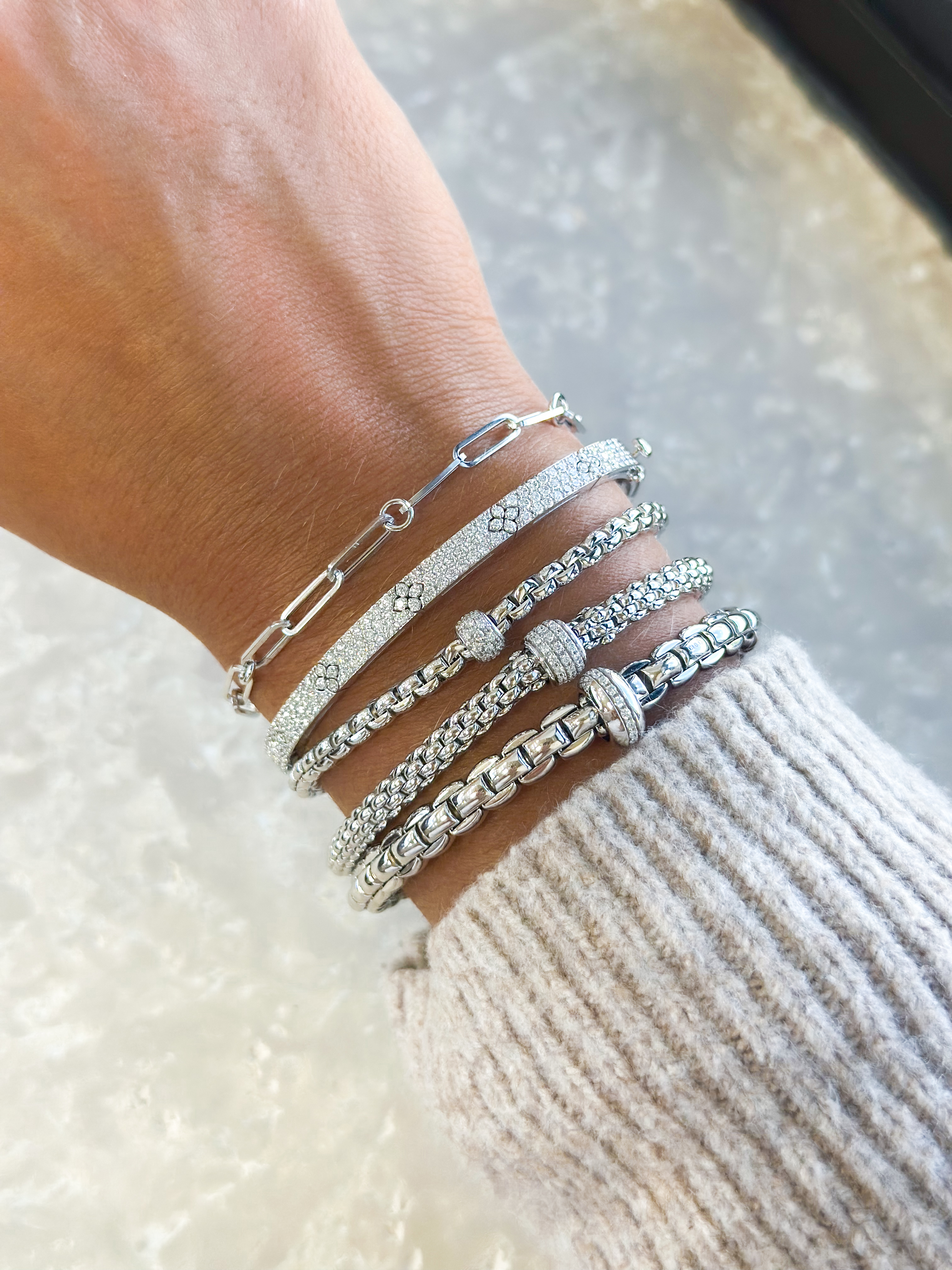 A close-up of three delicate diamond pendant necklaces on a dark leather backdrop.