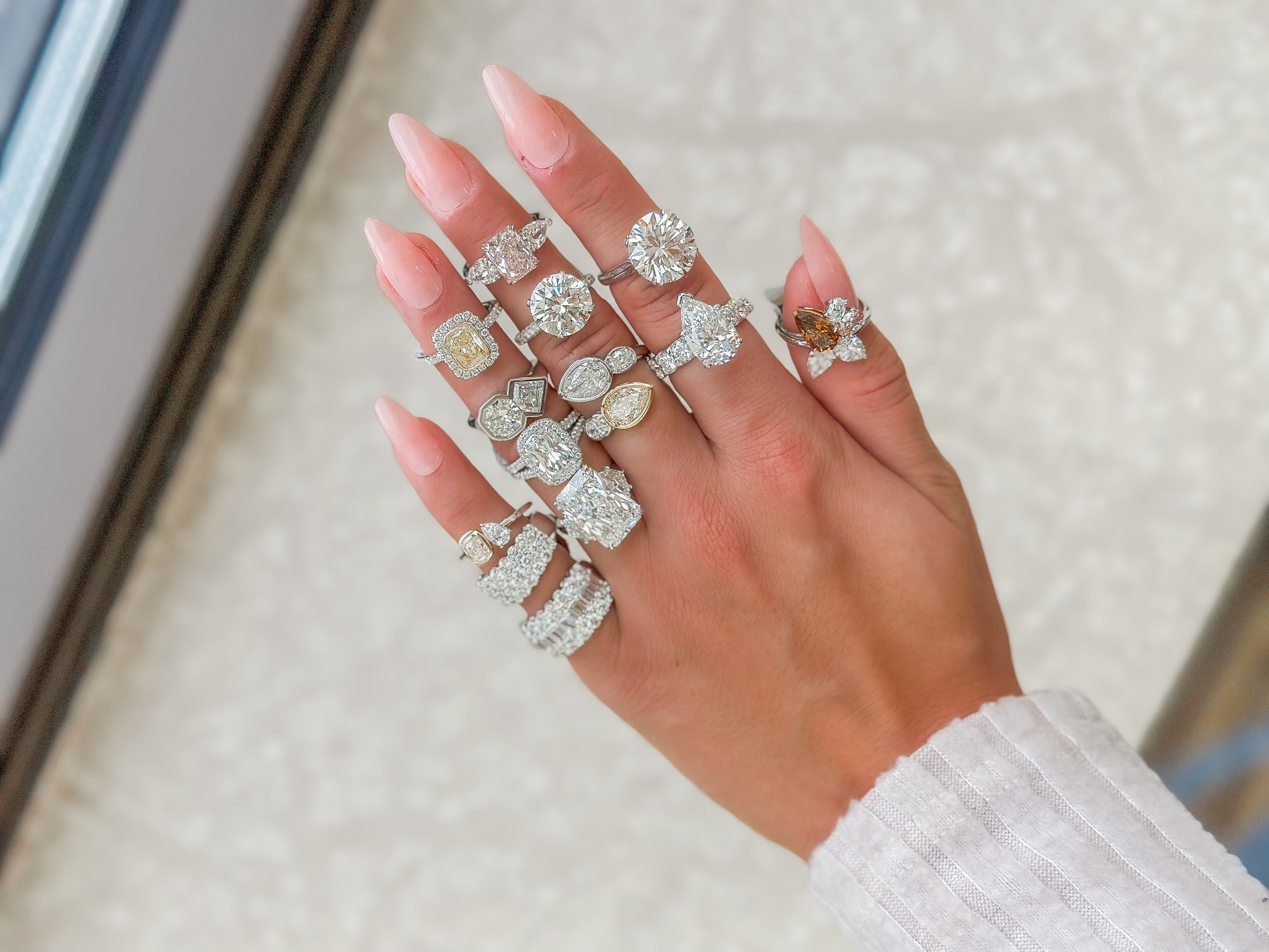 A close-up of a newly engaged woman’s hand held by her partner, a solitaire engagement ring on her finger.