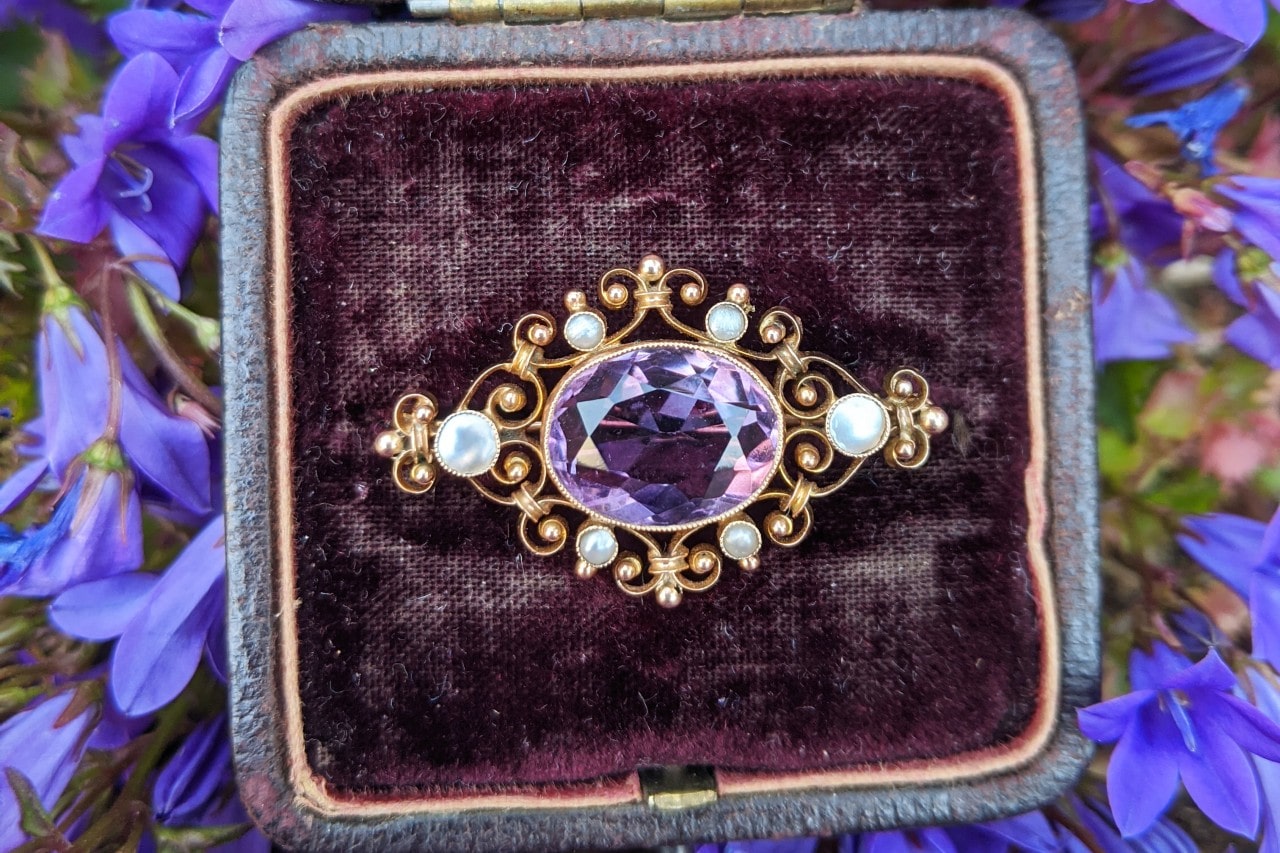 a piece of jewelry resting on a pillow surrounded by flowers