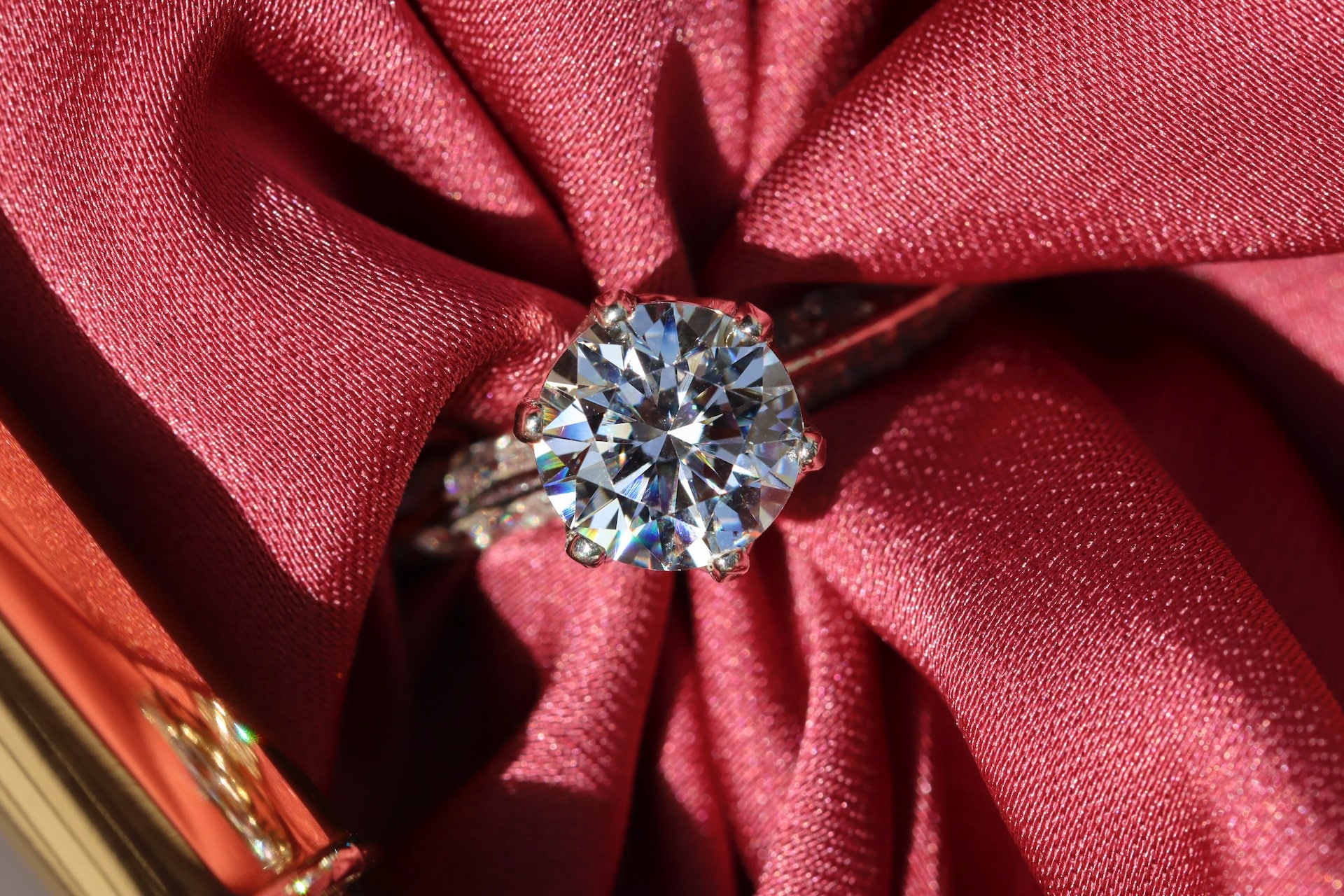 a solitaire diamond engagement ring with a red cloth threaded through it