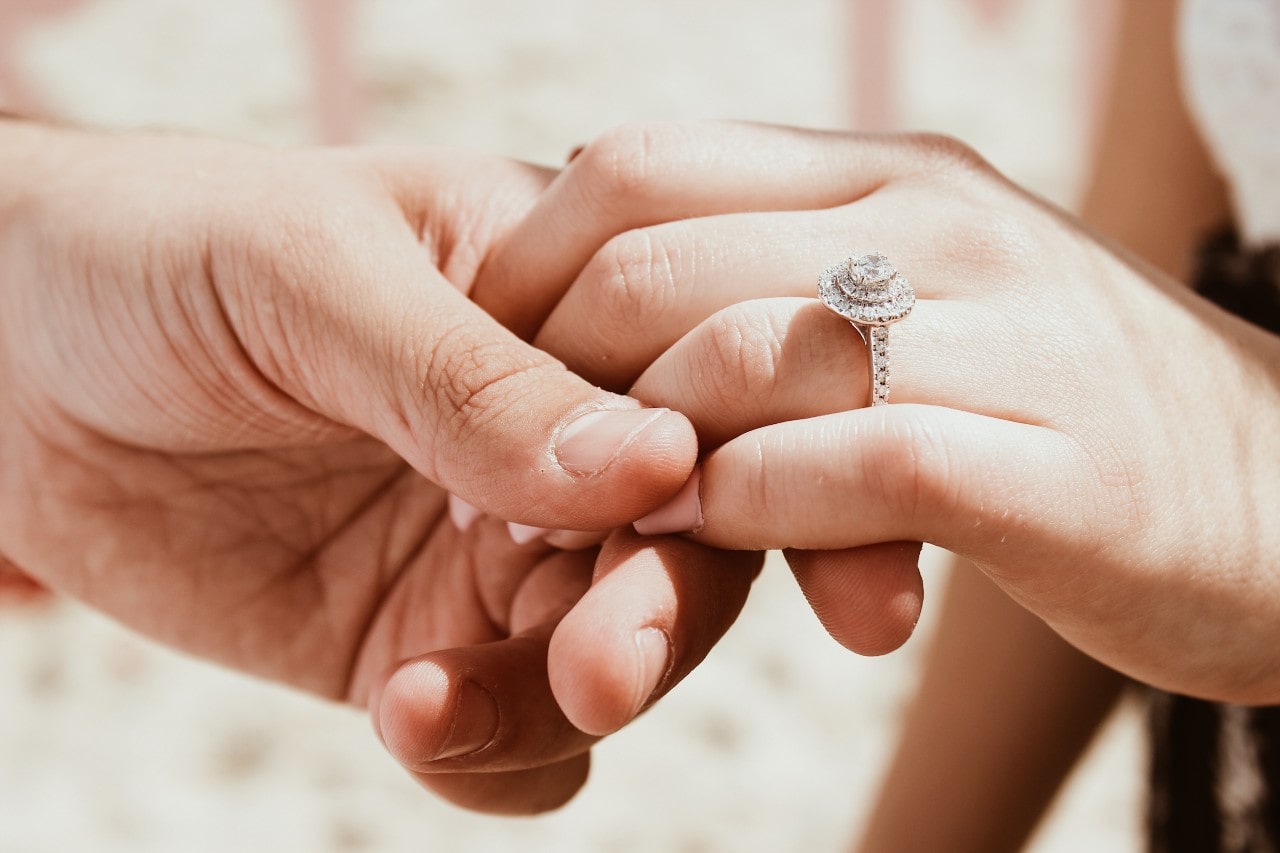 a man holding a woman’s hand wearing an engagement ring