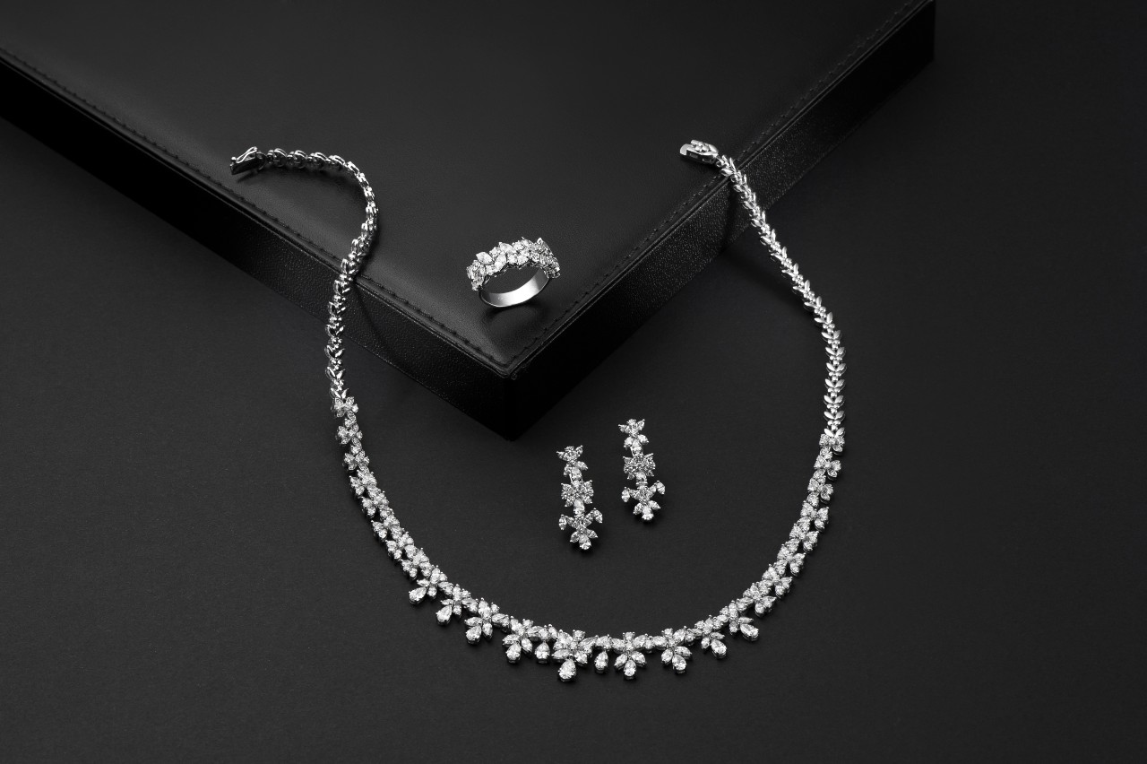 Elegant diamond jewelry set on a black background includes a sparkling necklace, a ring, and matching earrings
