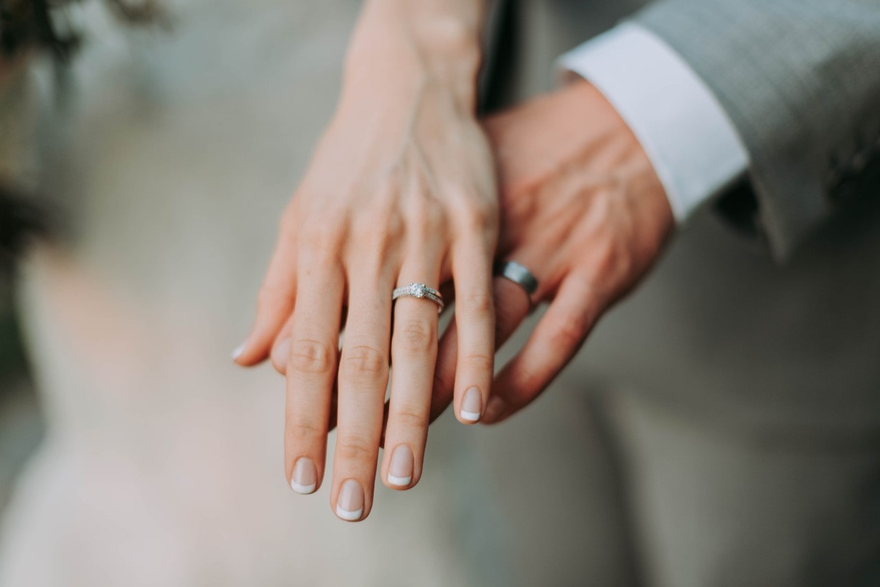 a man and woman’s hand wearing their wedding bands