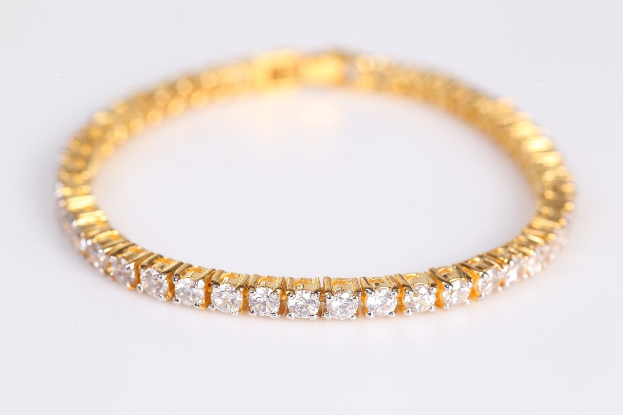 a yellow gold diamond tennis bracelet on a gray surface