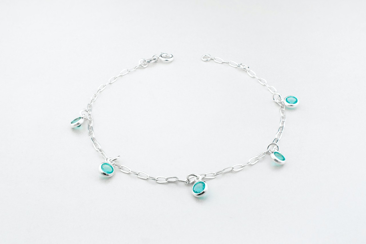 A white gold station bracelet featuring bezel set blue gemstones on a white background.