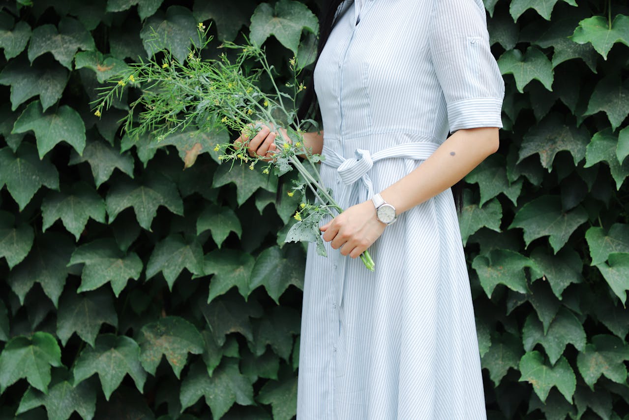 a woman in a blue dress holding flowers and wearing a monochrome white watch