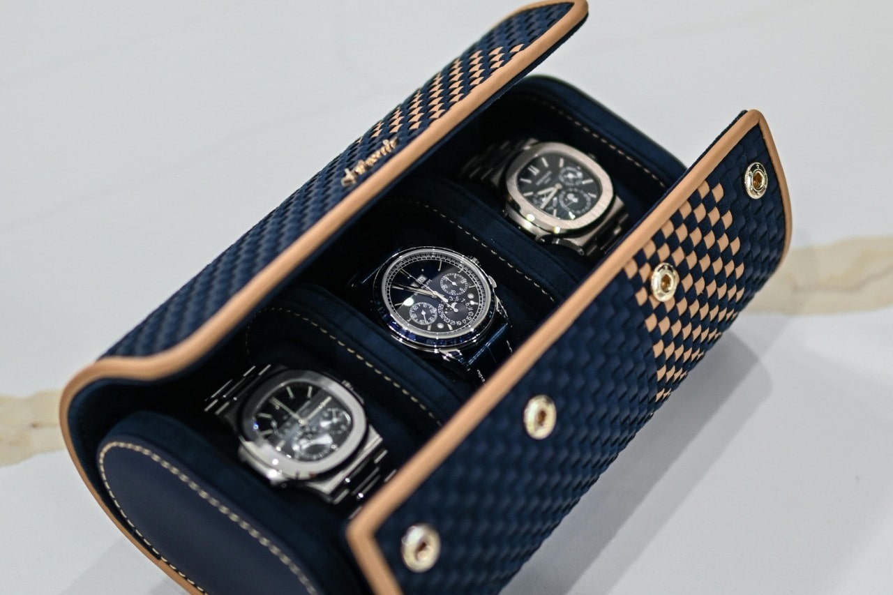 A luxurious blue and tan checkered watch case holds three elegant watches with metallic faces, conveying sophistication and style.