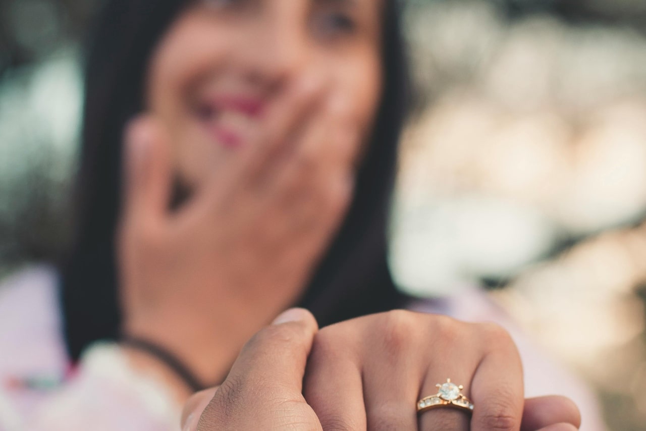 A close-up of a newly engaged woman’s hand held by her partner, a solitaire engagement ring on her finger. A close-up of a newly engaged woman’s hand held by her partner, a solitaire engagement ring on her finger.