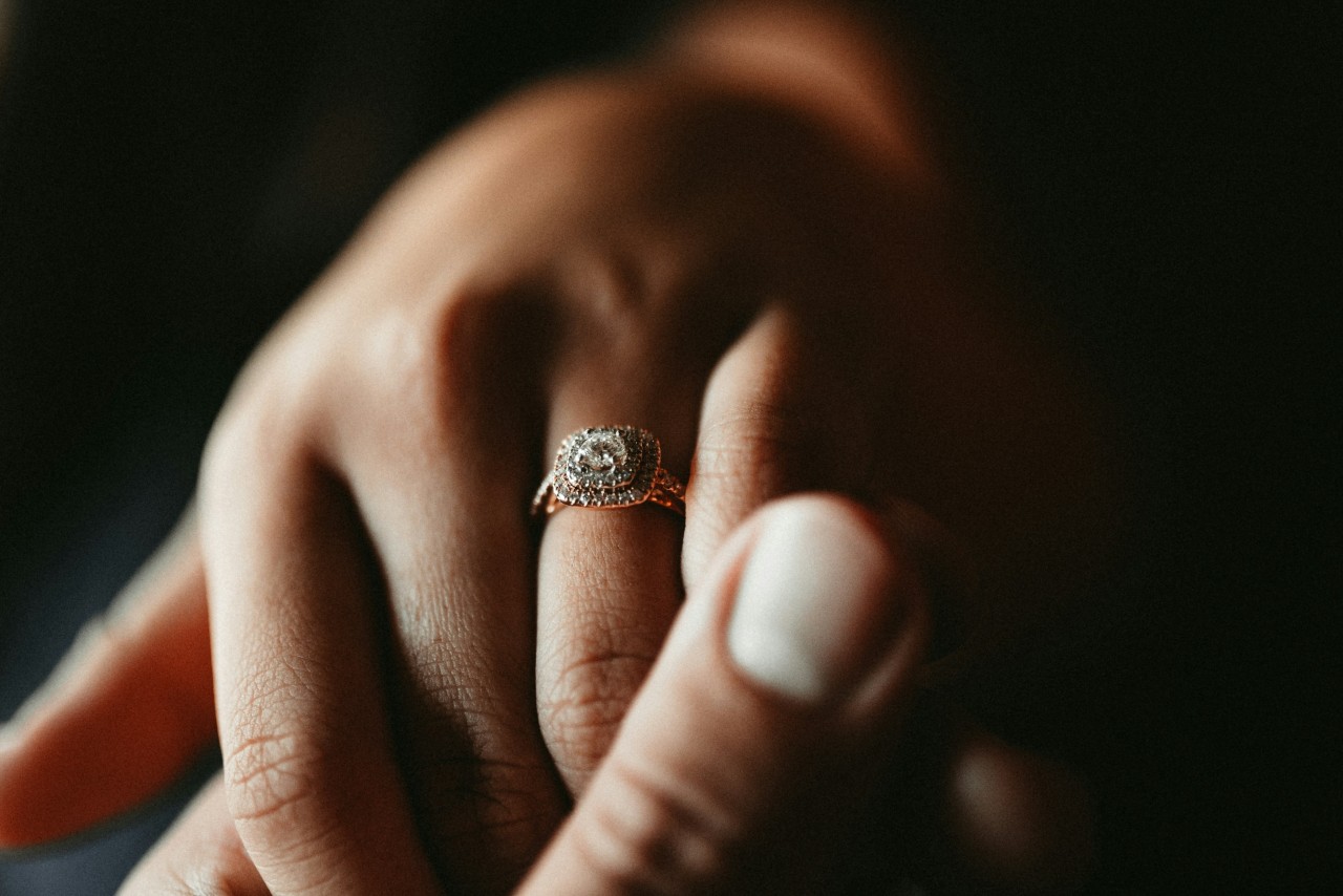 A close-up of a woman’s hand, with emphasis on her ornate halo engagement ring. A close-up of a woman’s hand, with emphasis on her ornate halo engagement ring.