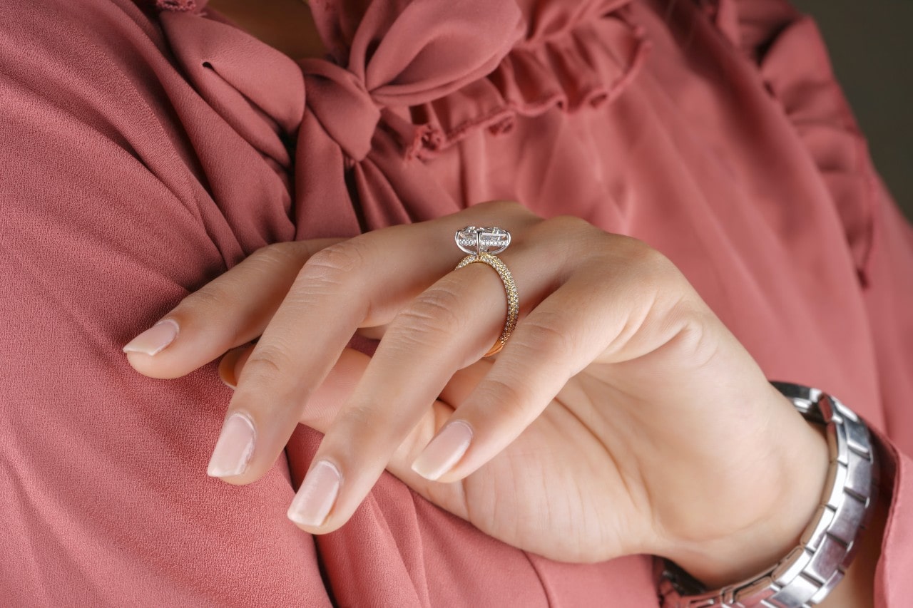 A businesswoman inspects her side stone oval-cut engagement ring.