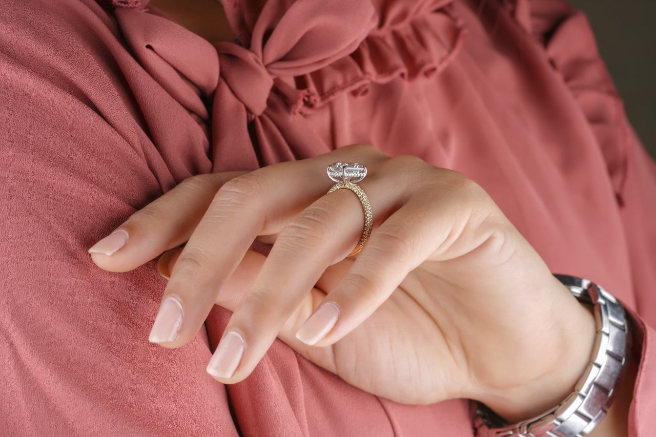 A businesswoman inspects her side stone oval-cut engagement ring. A businesswoman inspects her side stone oval-cut engagement ring.