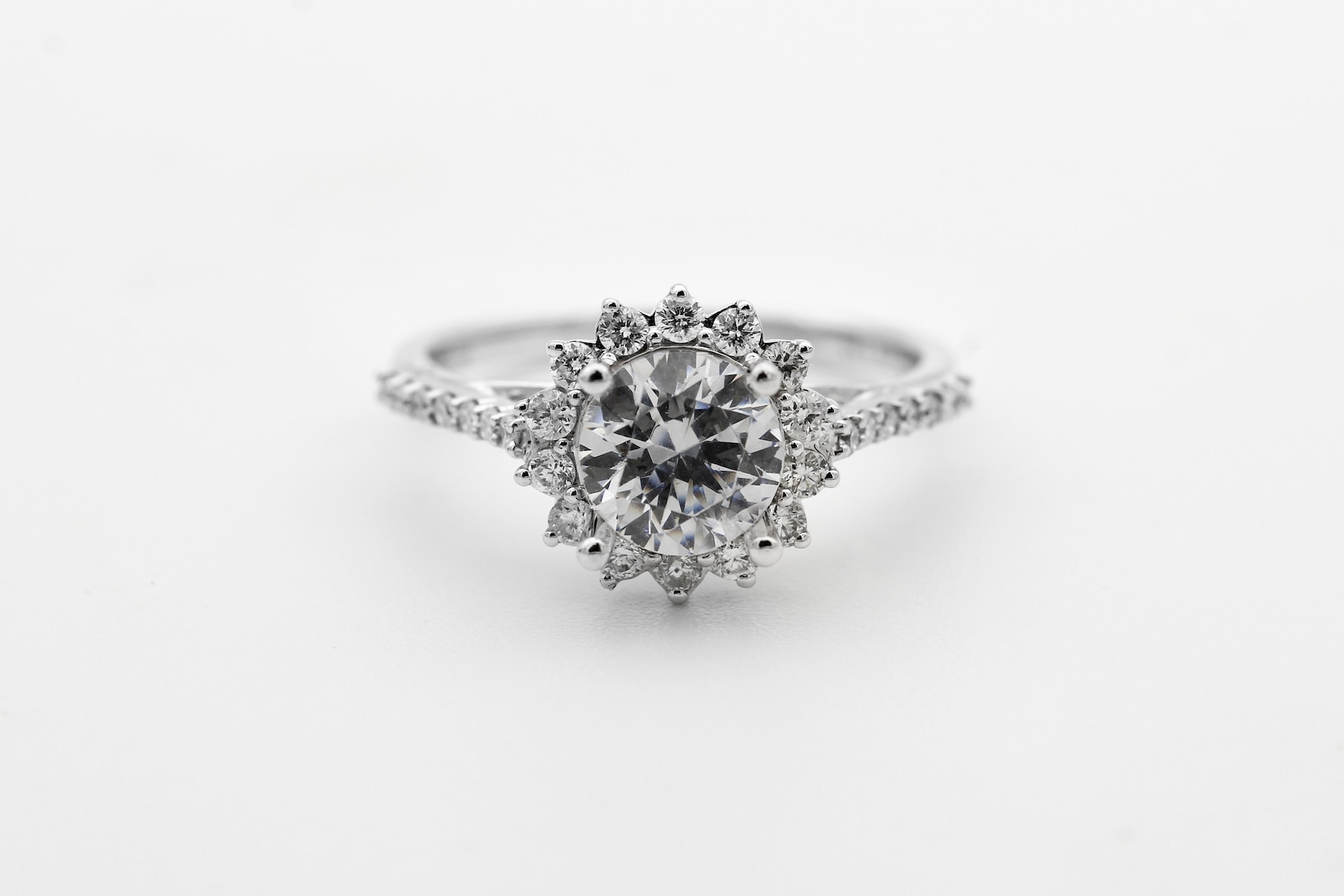 a round cut engagement ring featuring a halo of diamonds and side stones a round cut engagement ring featuring a halo of diamonds and side stones