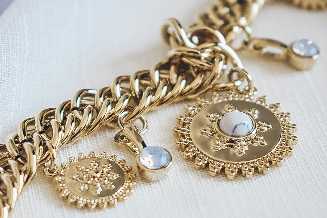 close up image of a chunky gold chain with sun motifs and gemstones