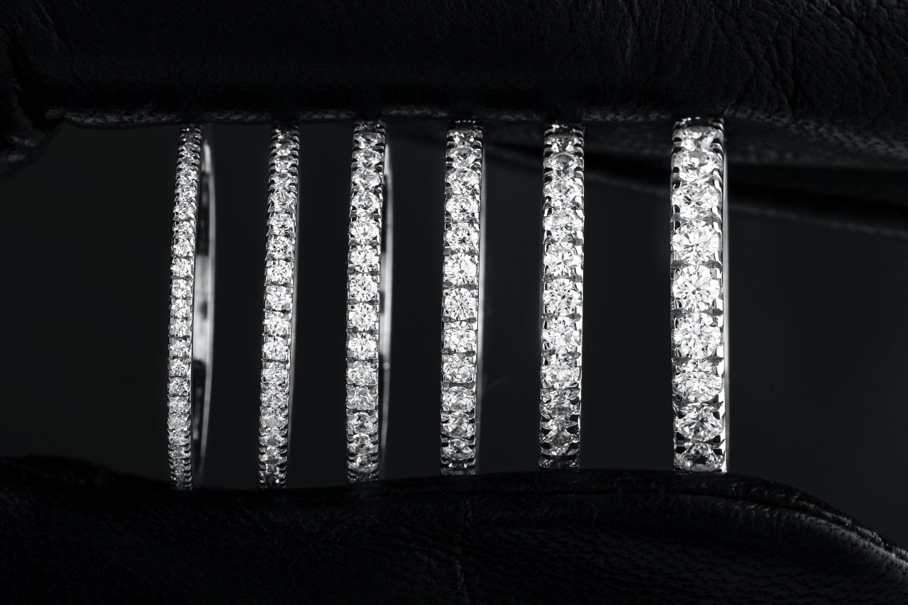 A close-up of six white gold bands in incrementally larger widths, all adorned with sparkling diamonds.