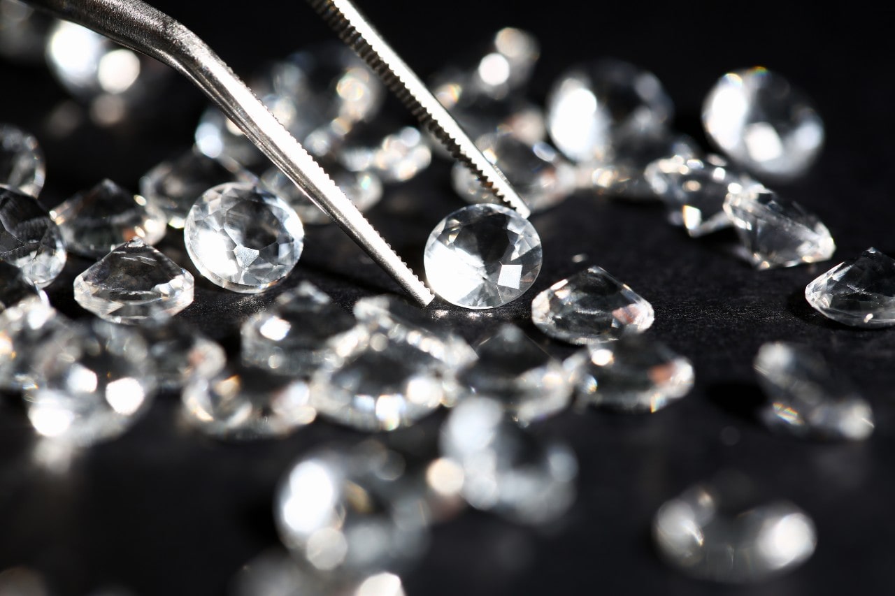 An assortment of round cut diamonds, one in a pair of jeweler’s tweezers An assortment of round cut diamonds, one in a pair of jeweler’s tweezers
