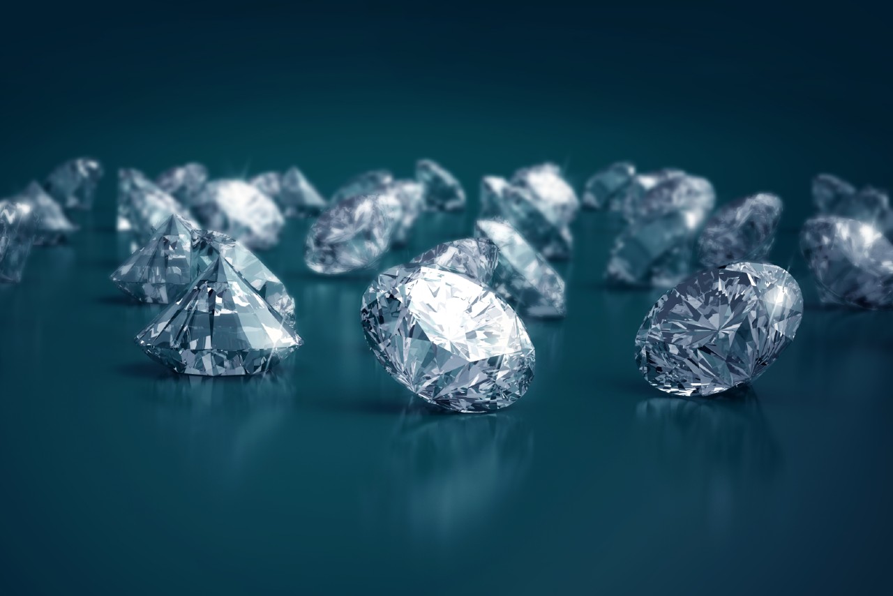 A wide selection of round-cut diamonds sits on a greenish-blue background