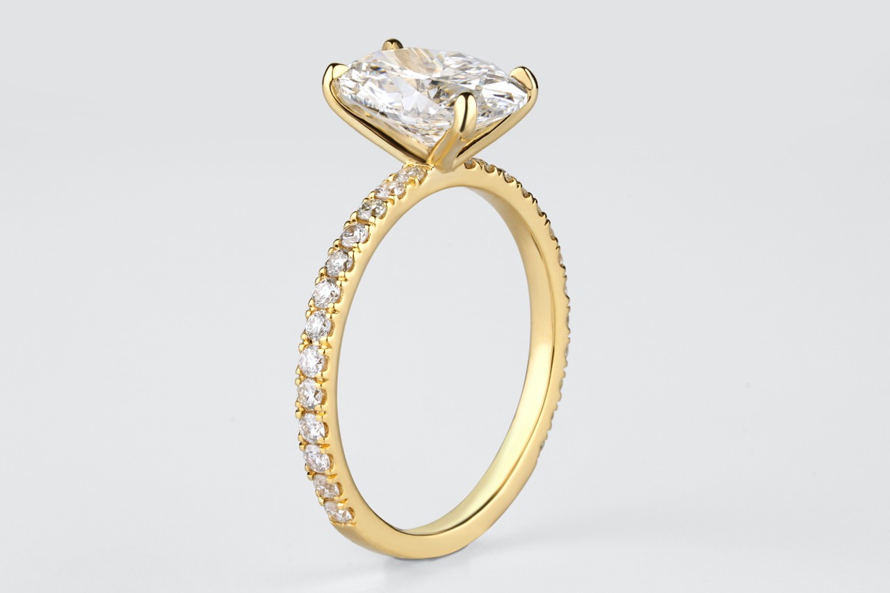 A yellow gold side stone engagement ring with one oval cut center stone. A yellow gold side stone engagement ring with one oval cut center stone.