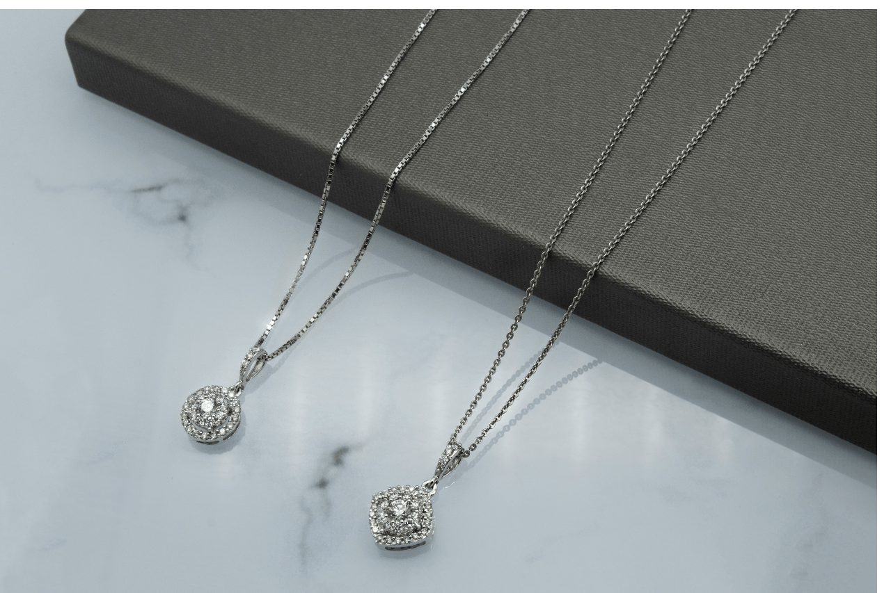 Two silver halo necklaces, one with a round halo and the other square, displayed on a gray textured box.