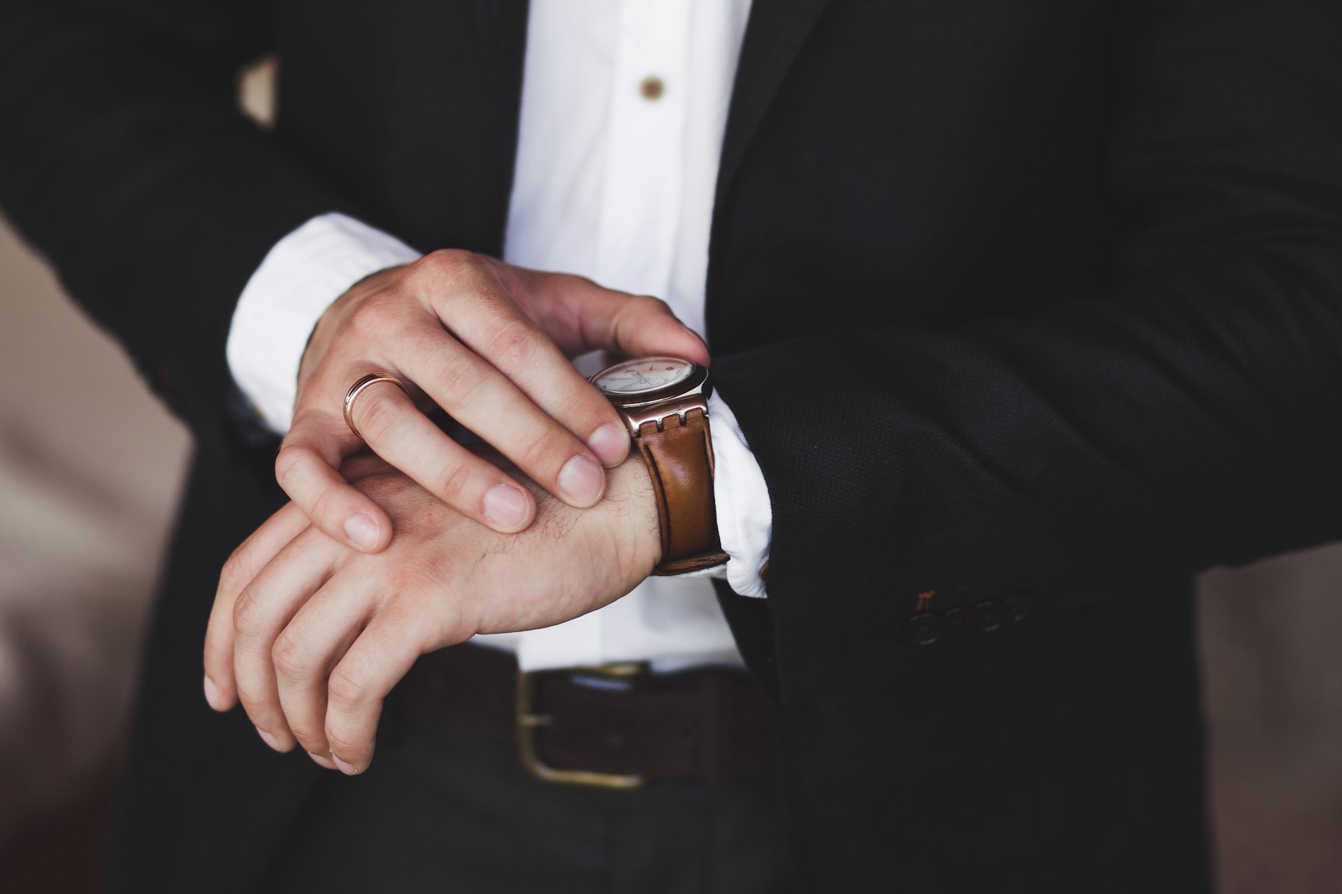 A close-up of a well-dressed man checking his luxury watch. A close-up of a well-dressed man checking his luxury watch.