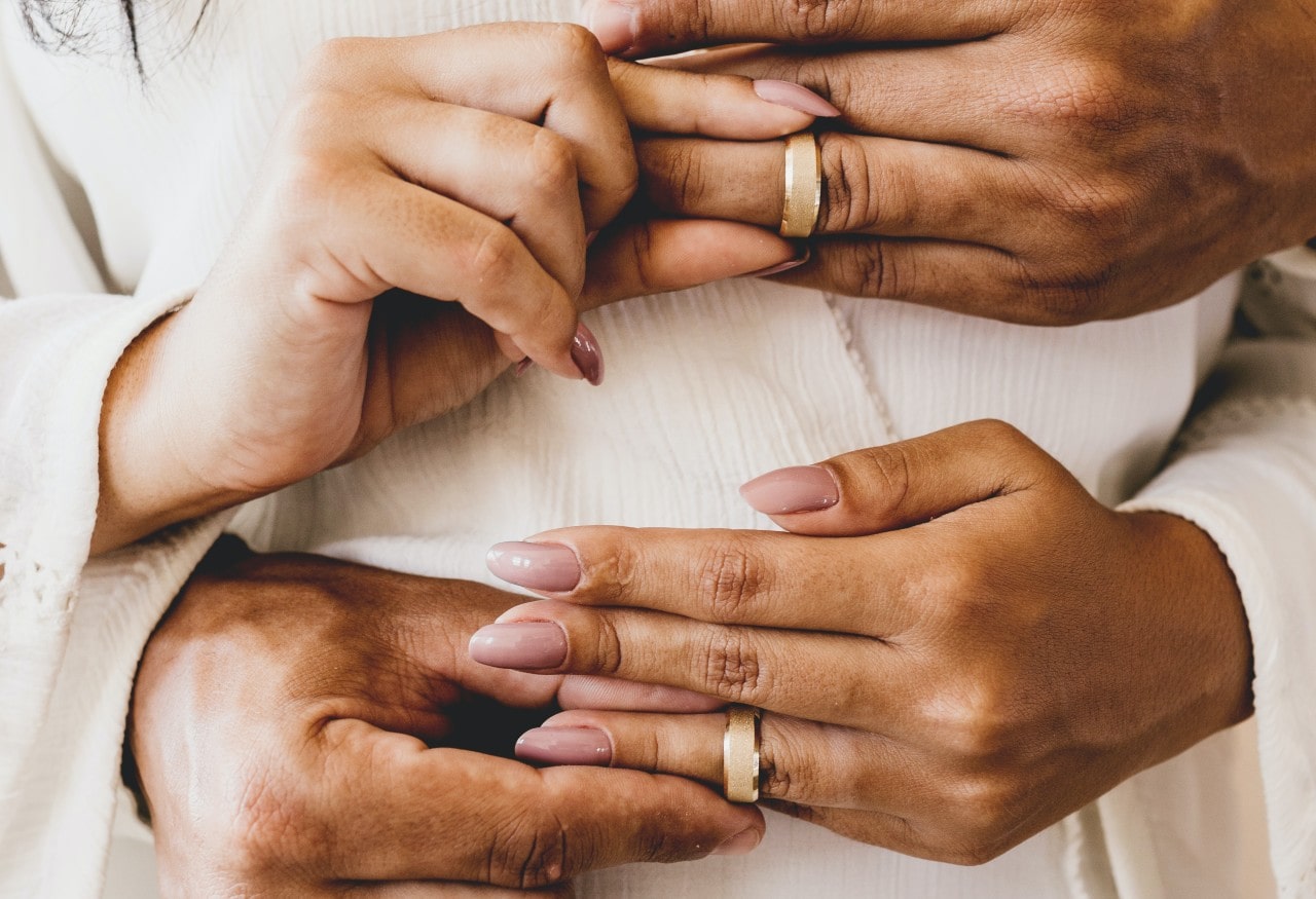 A man and woman simultaneously placing matching rings on each others’ fingers