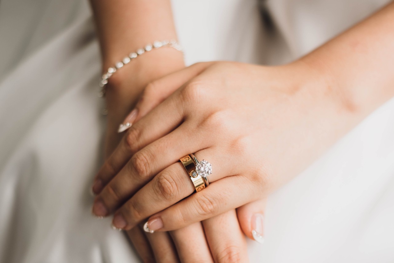 A close-up of a bride’s hands resting on her lap, a matching bridal stack on her finger.