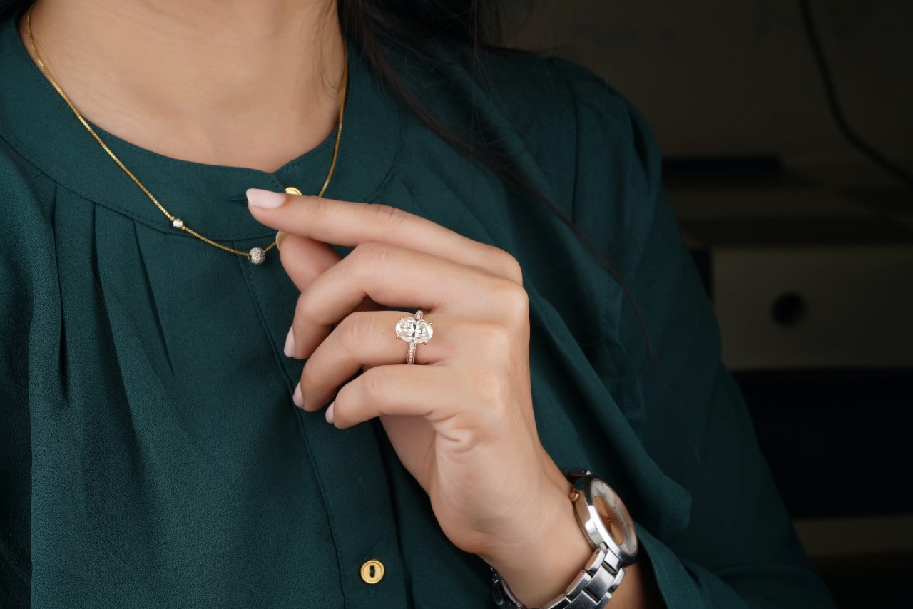 a woman touches her necklace wearing her engagement ring.