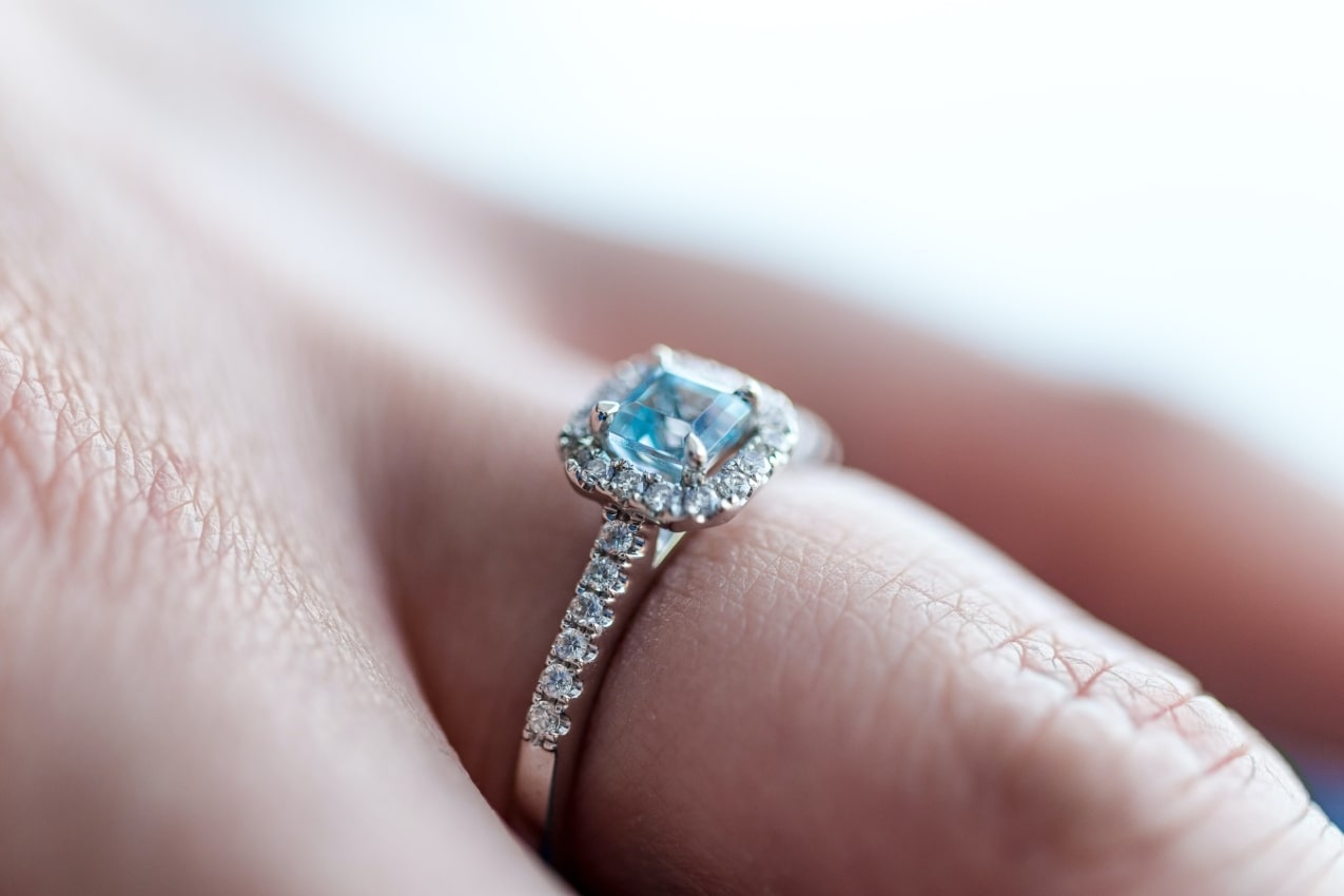 A blue topaz halo engagement ring on a woman’s finger.