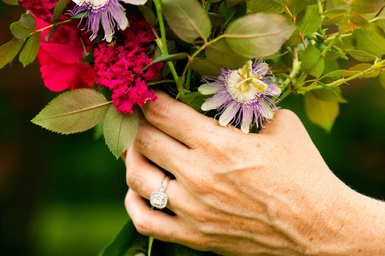 A woman holding a bouquet of flowers wears a halo ring.